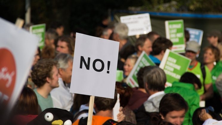 Demonstrierende Menschen und ein Schild mit der Aufschrift "no!"